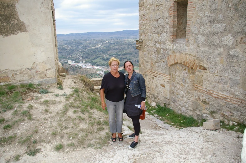 two woman stand next to each other in a stone structure