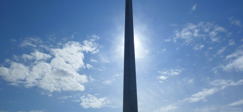 the top of a light pole against a blue sky with clouds