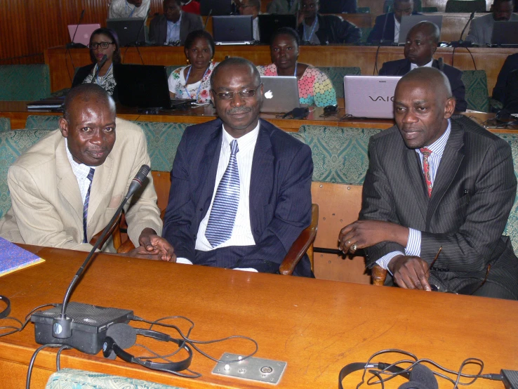 three men sitting next to each other at a desk