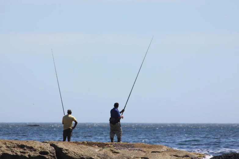 two men standing on the side of the ocean