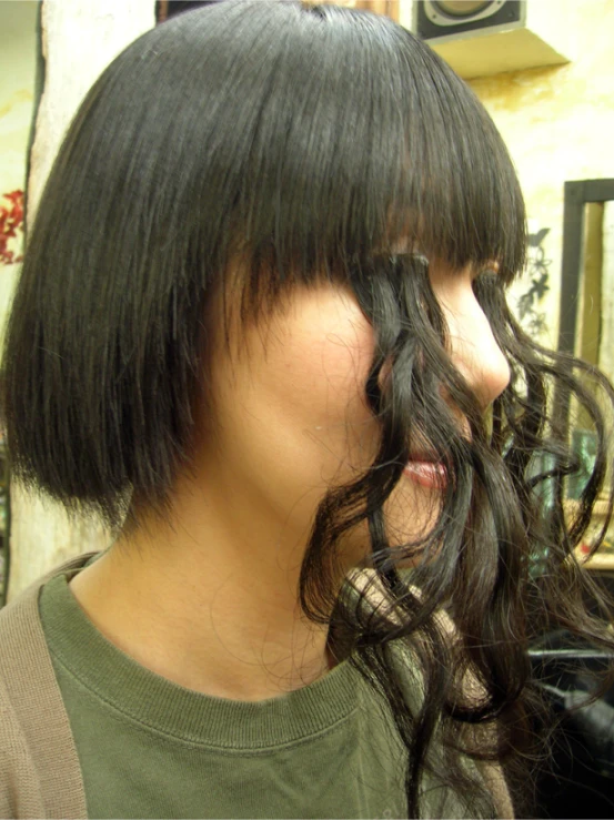 a woman has black hair while standing by some mirror