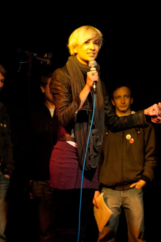 a young lady holds up a microphone as two people stand near her