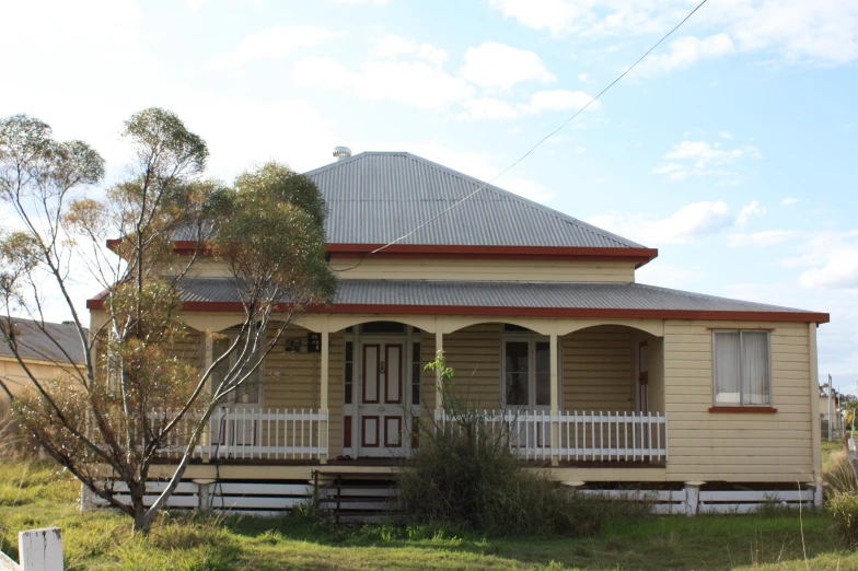 a small yellow house with a large front porch