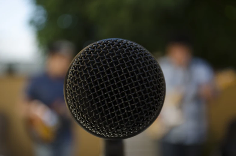 a black microphone that has a man behind it playing music