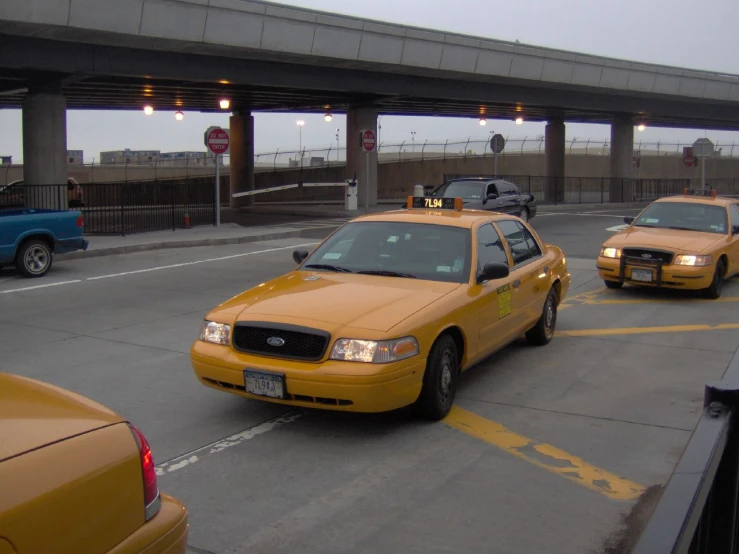 a bunch of taxi cabs driving down a street next to a bridge