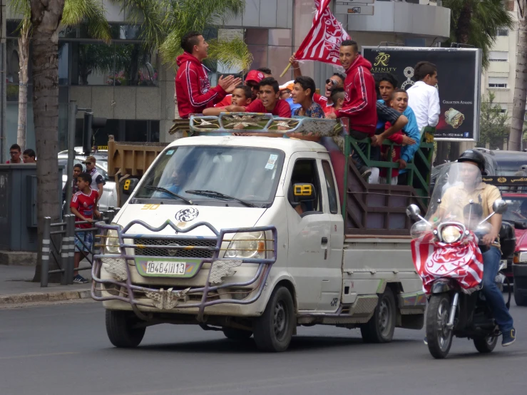 a man rides a motorcycle and carries an american flag while the crowd watches