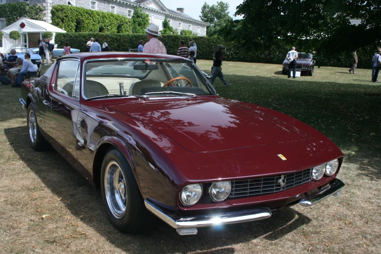 a burgundy, convertible car in a field of grass