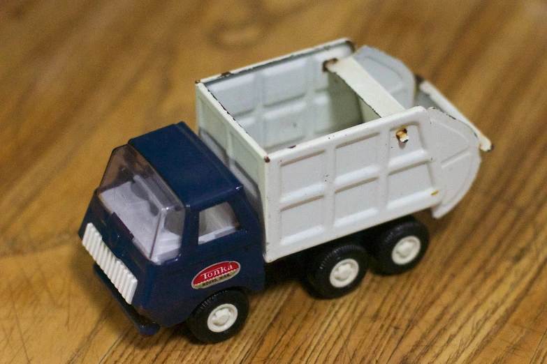 a toy garbage truck sitting on a wooden floor