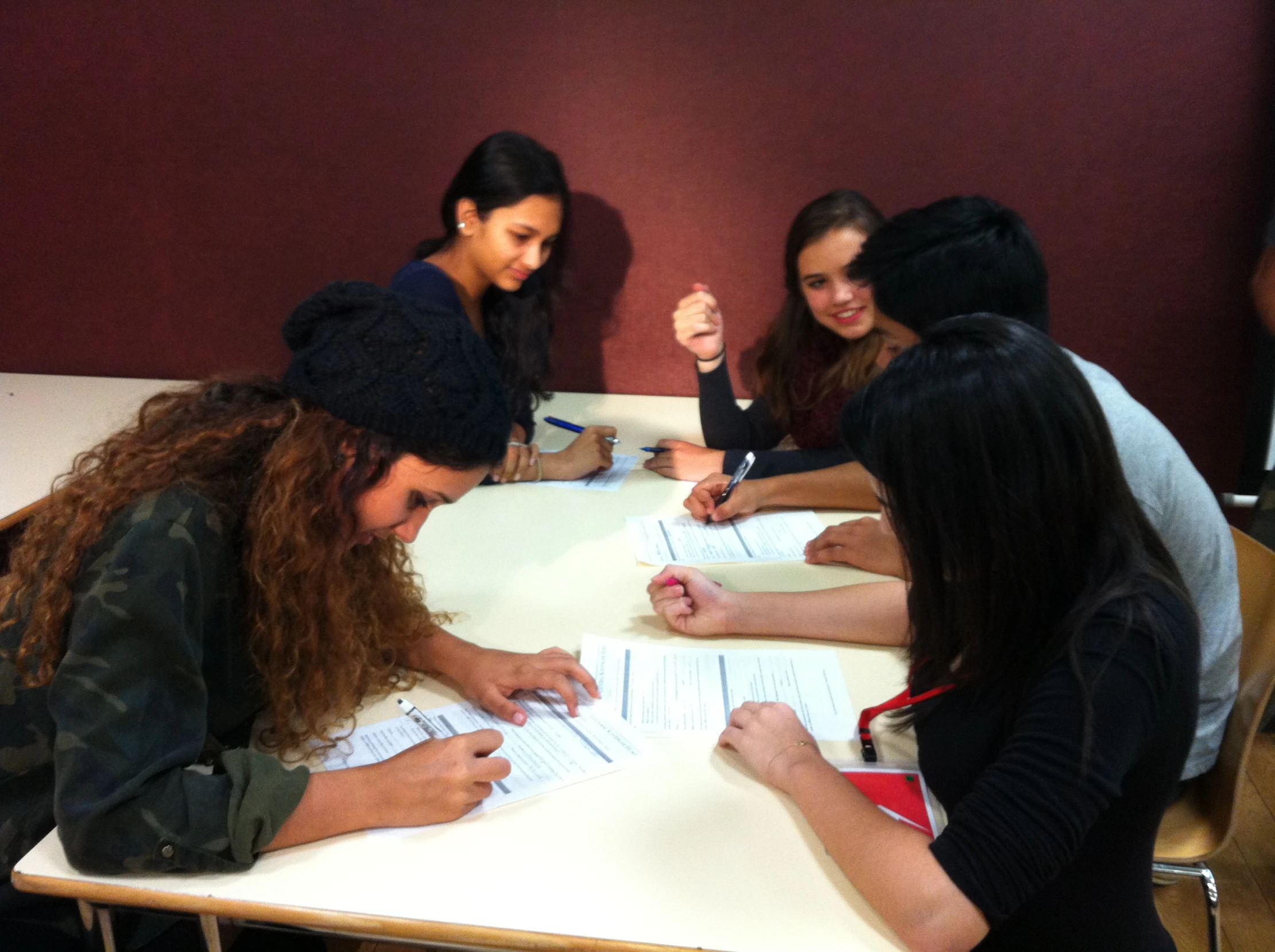 a group of people writing on top of a white table