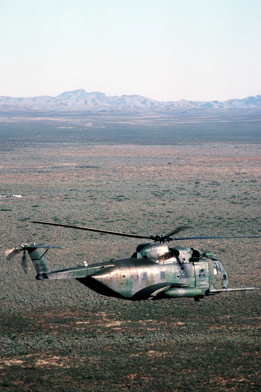 a helicopter is flying in the air over some sand