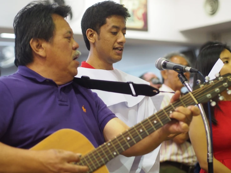 two men that are playing the guitar in a room