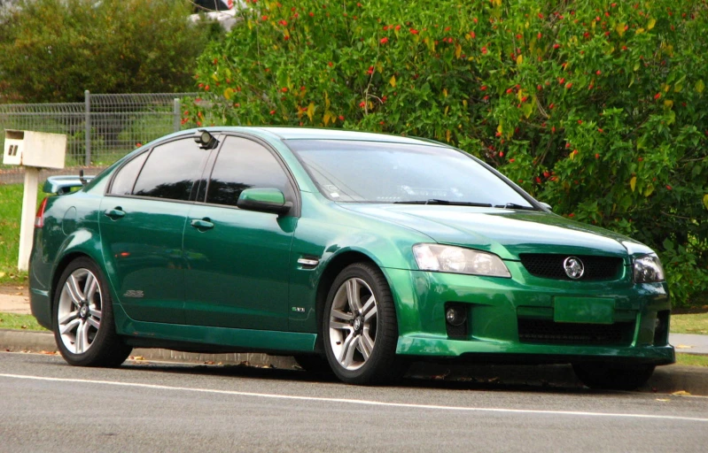 a green car is sitting on the side of a street