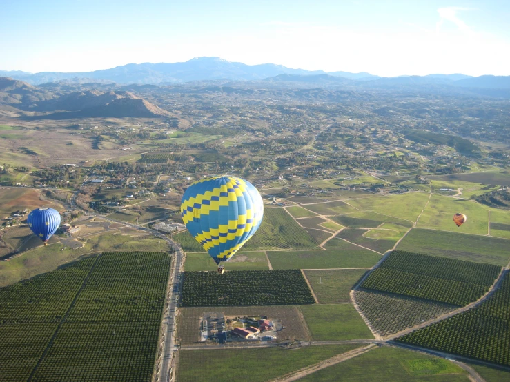 two  air balloons fly above an overview of a rural area