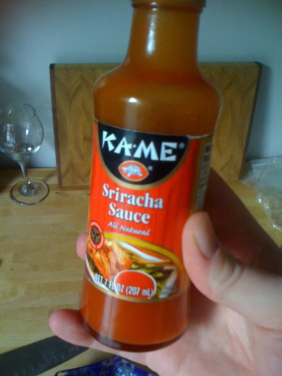 someone holding onto a bottle of sauce