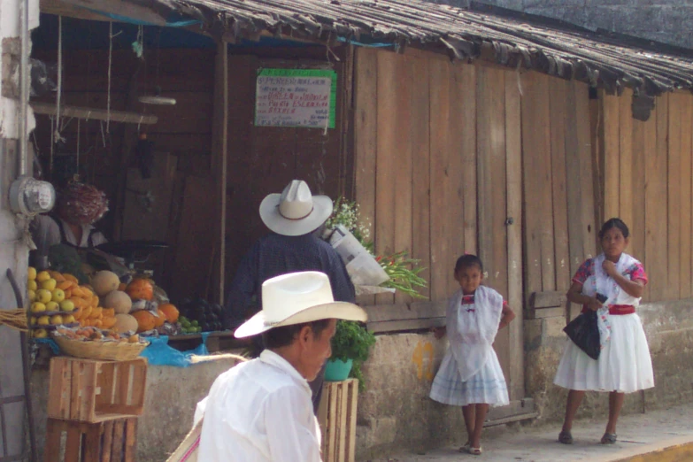 three s are walking on the street by a small store