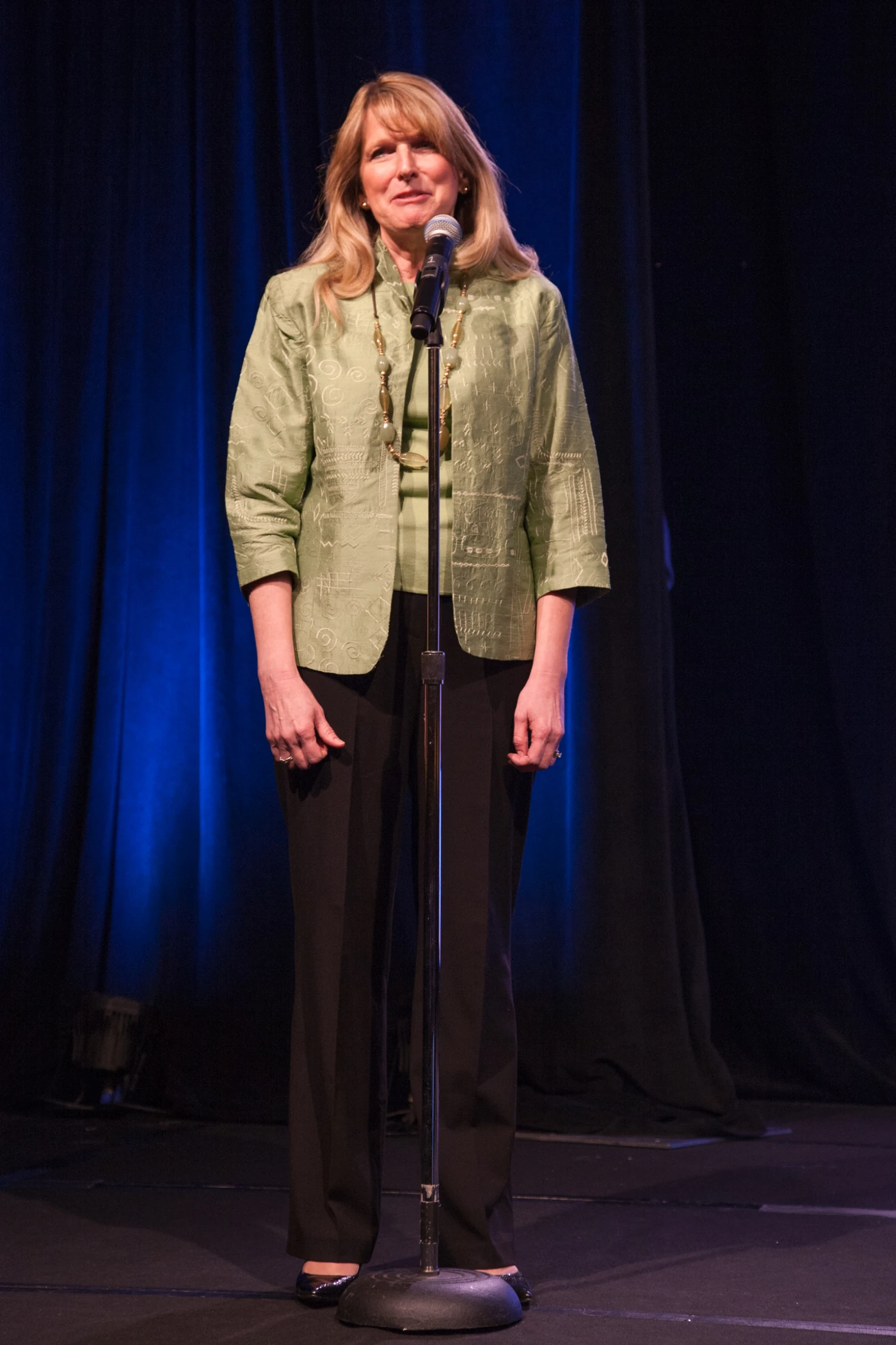 a woman standing behind a microphone in front of a curtain