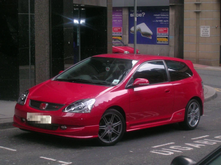 a small red car is parked next to an empty sidewalk