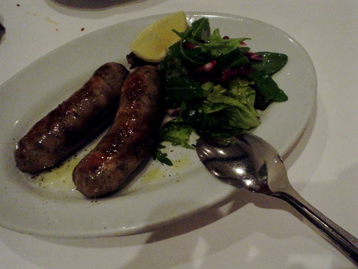 a plate with two sausages and salad on it