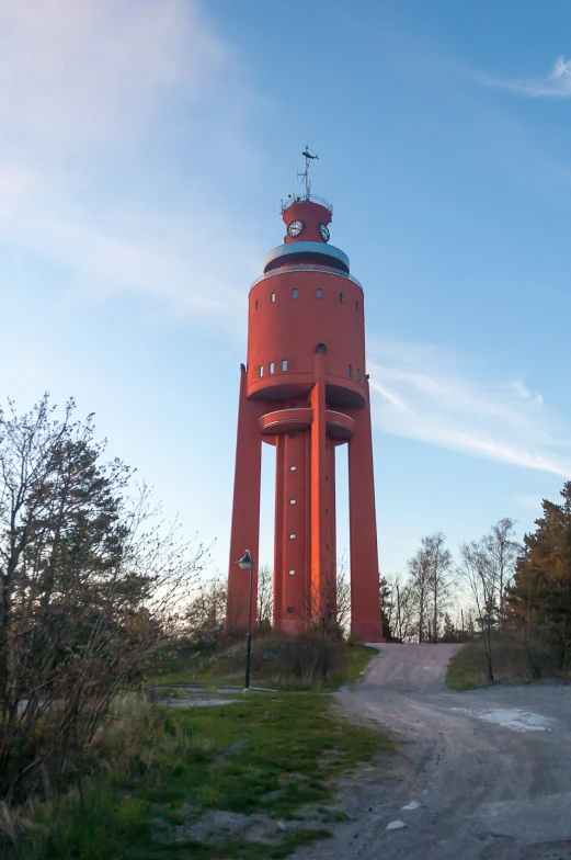 a tower with a cross on top in the middle of a dirt road