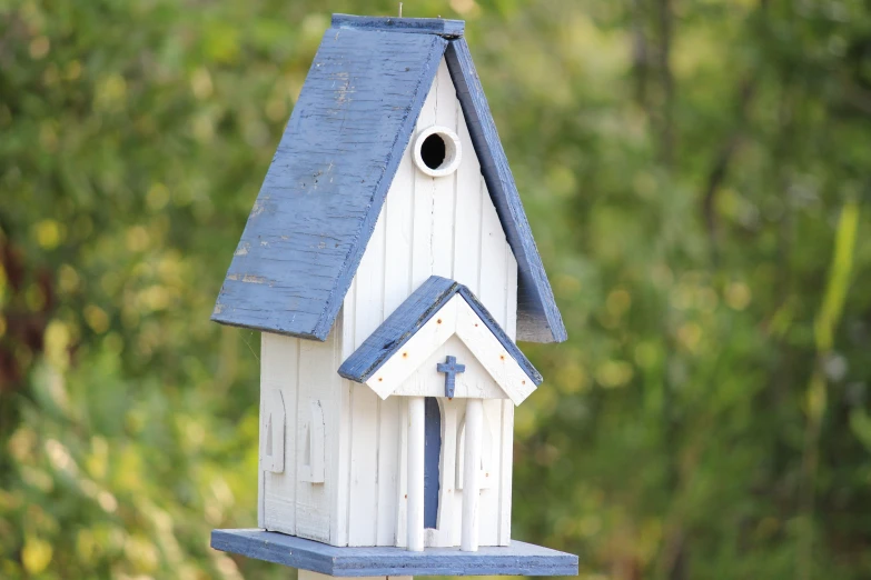 small white bird house with blue roof and weather guard