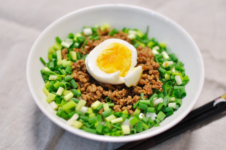 an egg on top of some green onions and seasonings