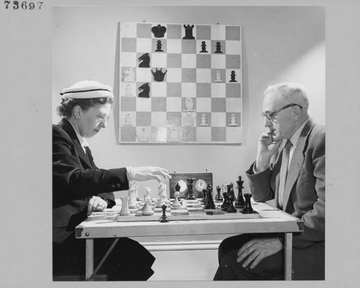 two people are sitting down playing chess