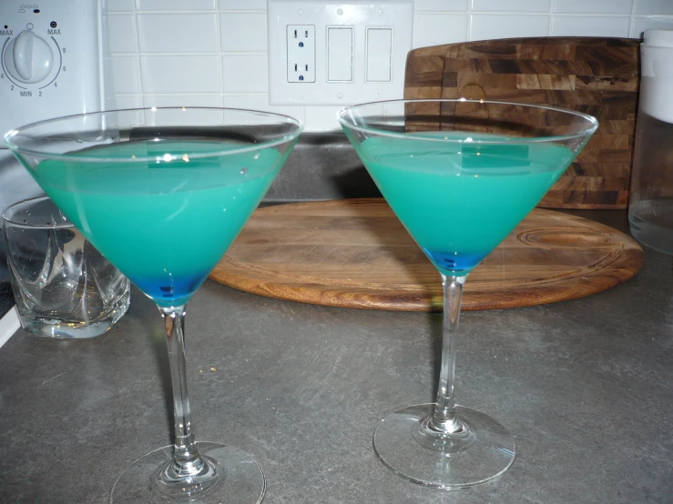 two glasses filled with blue liquid on top of a counter