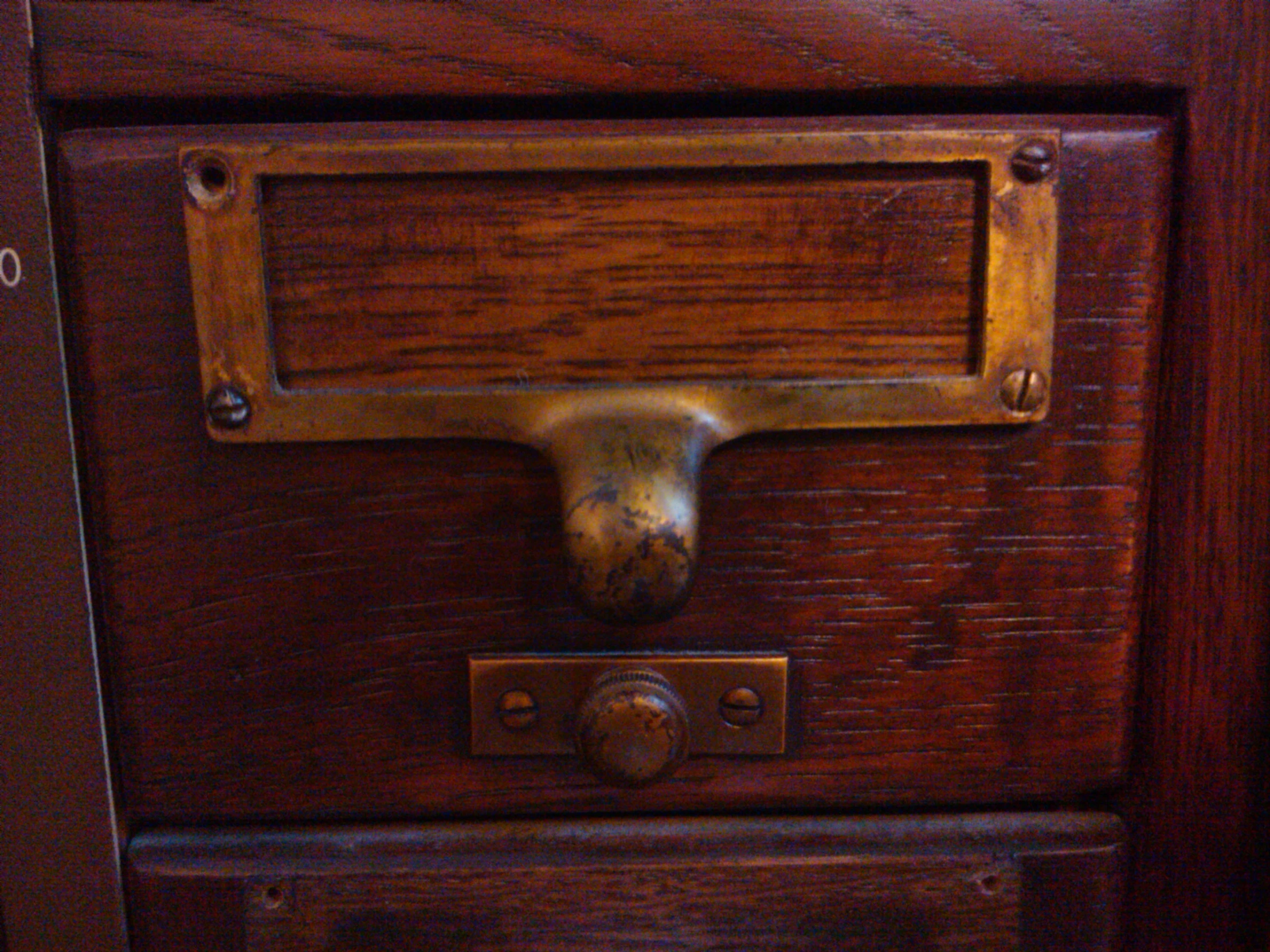 a drawer with an iron handle that is made of wood