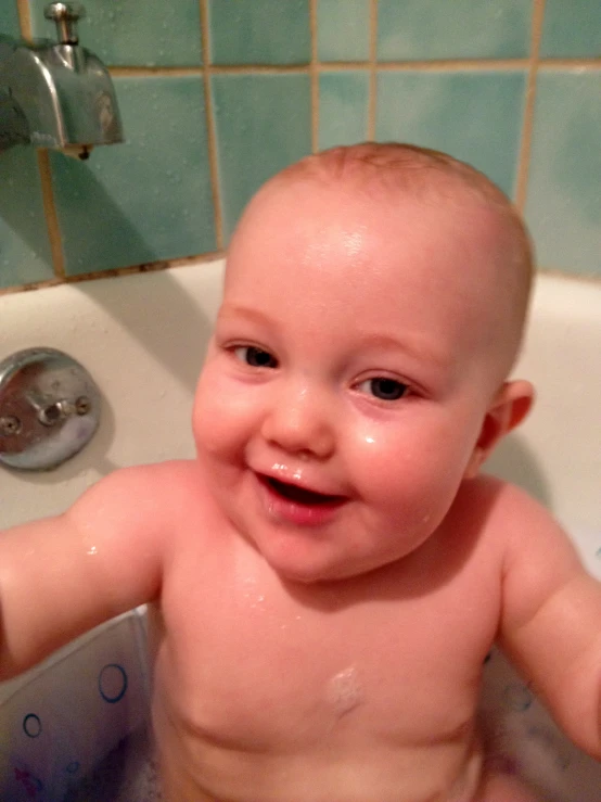 a baby in the tub smiling for the camera