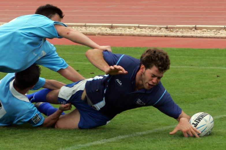 a rugby player falls to the ground while being tackled