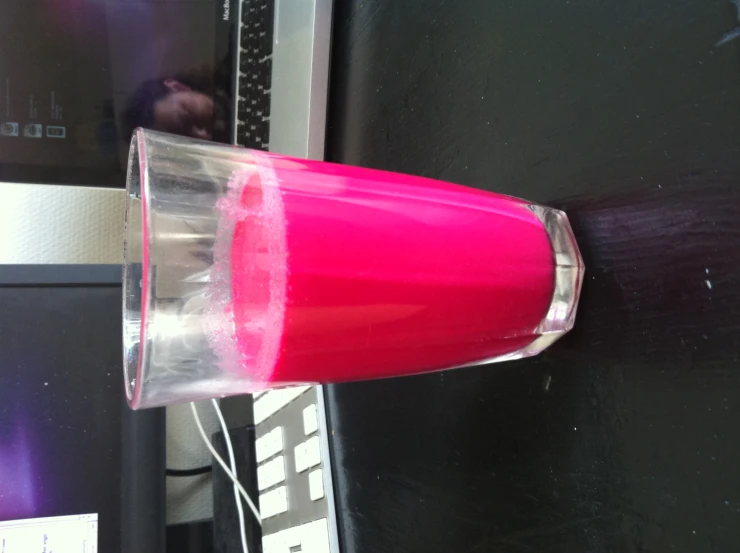 a glass with red liquid on a black table