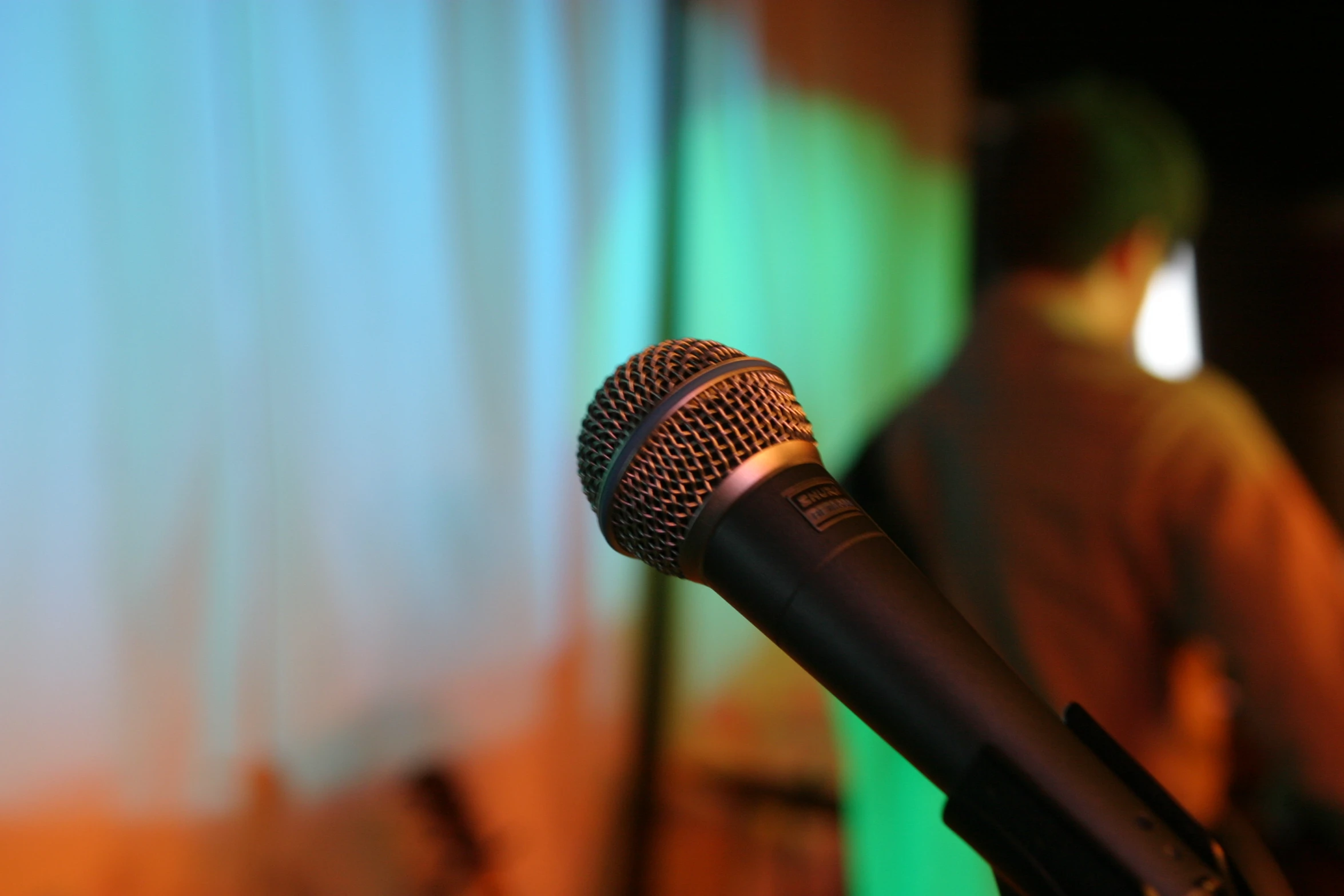 a microphone with a man speaking behind it