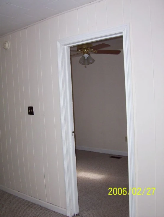 an empty white room with a ceiling fan and a door