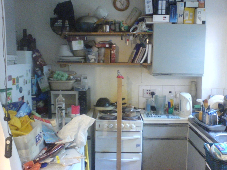 a messy kitchen with a cluttered stove and refrigerator