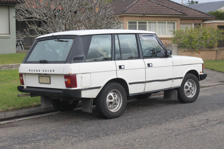 an old white land rover parked in the street