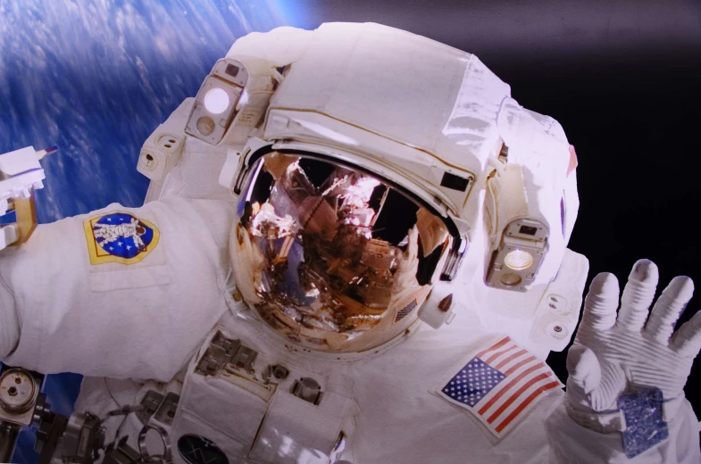 a close up of an astronaut holding up two hands