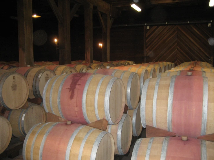 many wooden wine barrels with lights in the background