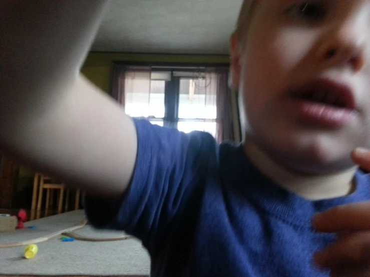 a small boy wearing a blue shirt has his arm in the air