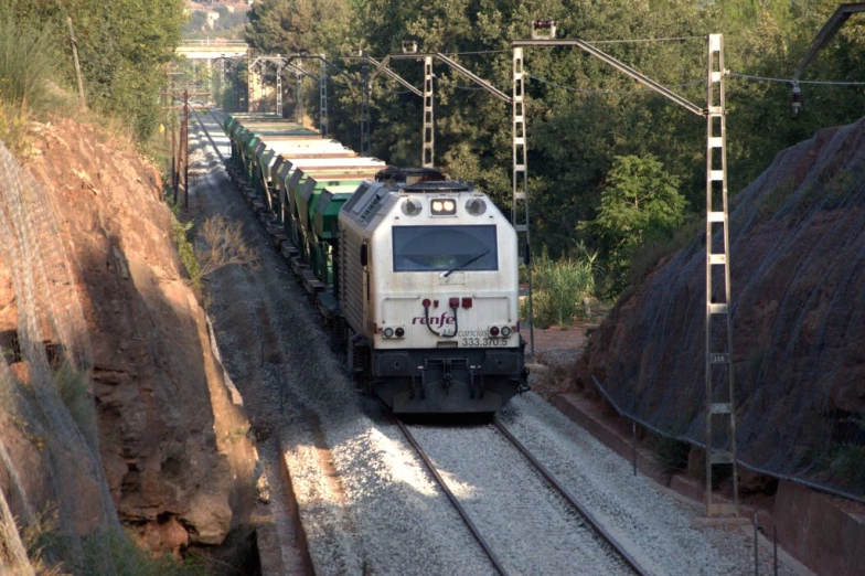 a train traveling past tall mountains next to trees