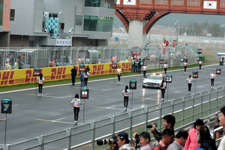 runners in uniform move along the road and watch people take pictures