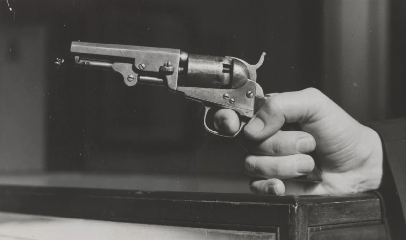 a person holds a miniature gun in their hand