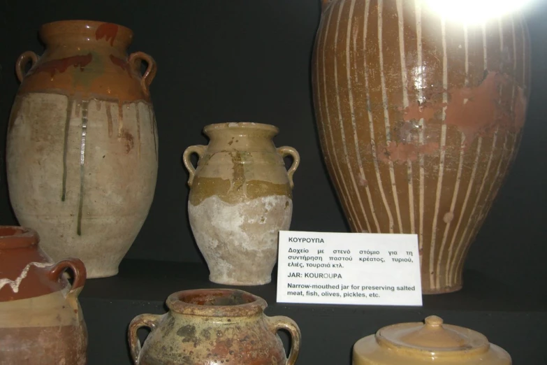 four old ceramic urns in various colors sitting on display