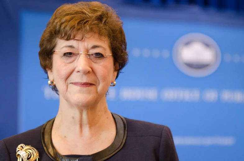 an older woman is standing in front of a blue wall