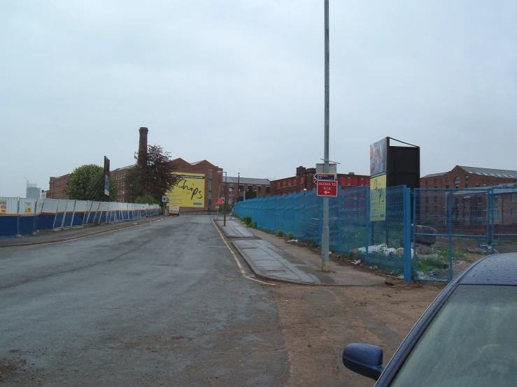 a blue fence sitting between two buildings next to a road