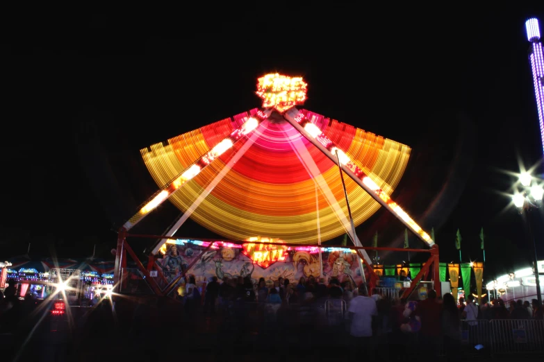 there are many people standing around the carousel at night