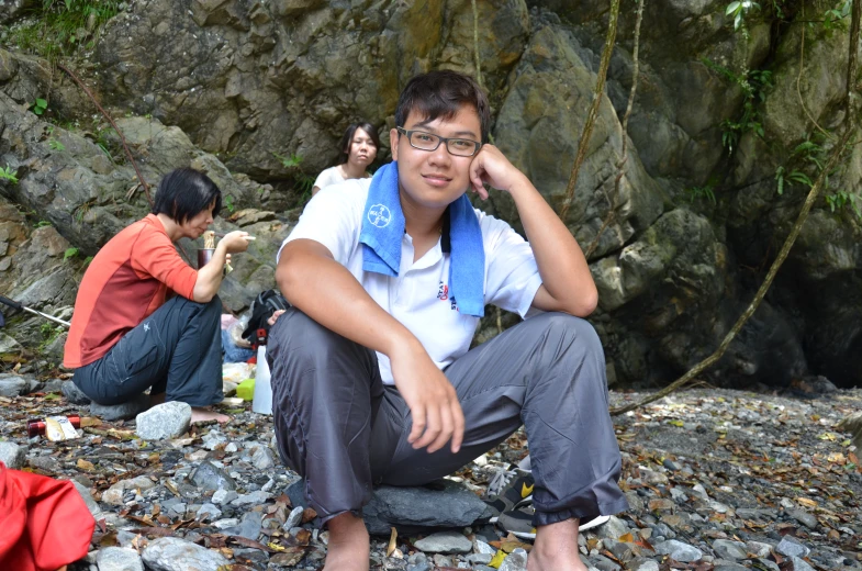 there are three people sitting on rocks at the beach