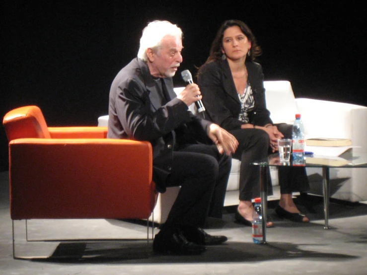 two people sitting in chairs and one of them is holding a microphone