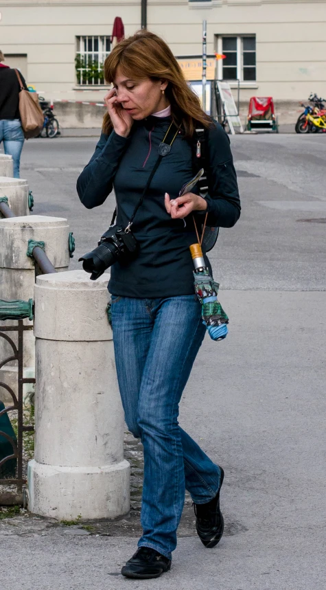 a lady walking by a man talking on his cell phone