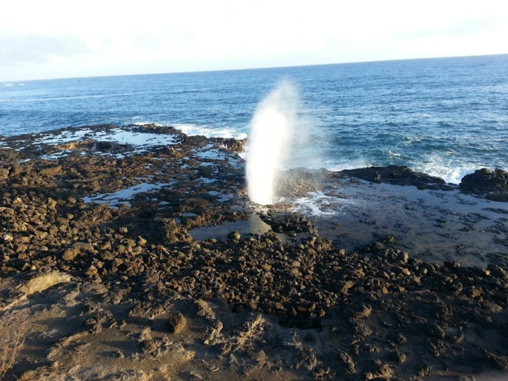 a big geyser is coming out of the rocks near the water
