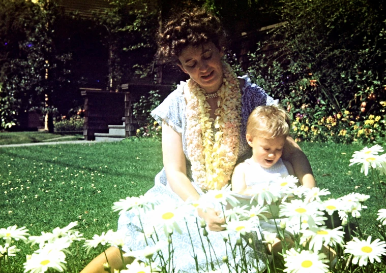 a woman holding a young child in the grass
